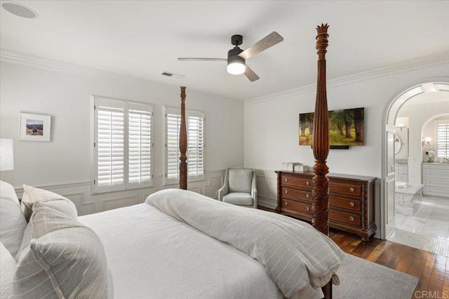 bedroom with ornamental molding, a wainscoted wall, visible vents, arched walkways, and wood finished floors