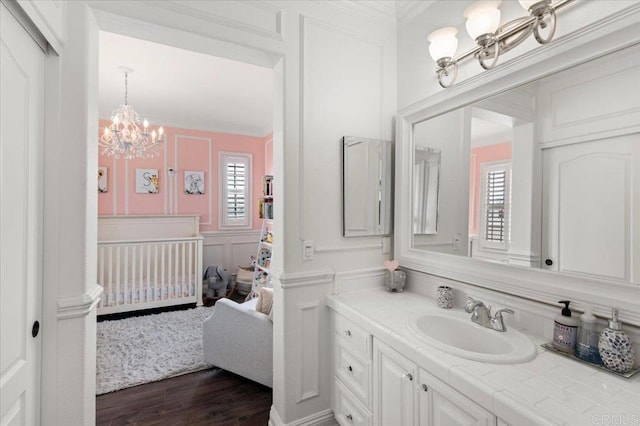 bathroom featuring a decorative wall, a notable chandelier, ornamental molding, and a healthy amount of sunlight