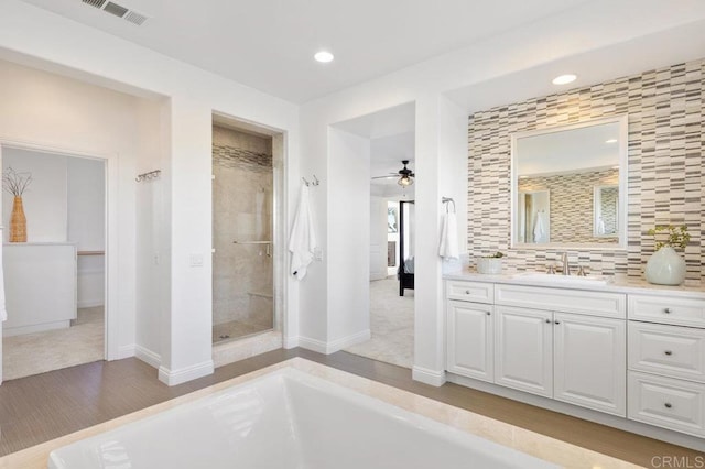 bathroom with a stall shower, vanity, ceiling fan, baseboards, and visible vents