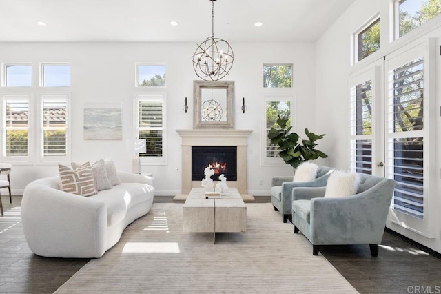 living room featuring recessed lighting, an inviting chandelier, wood finished floors, baseboards, and a glass covered fireplace