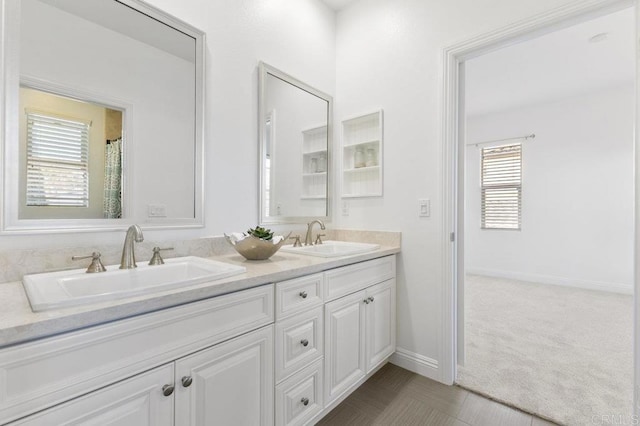 full bathroom featuring baseboards, a sink, and double vanity