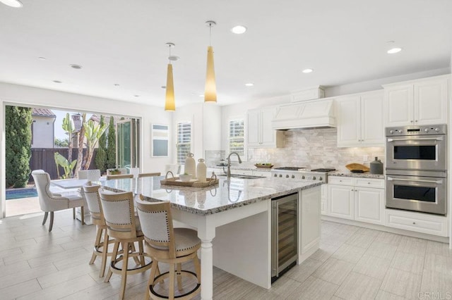kitchen with double oven, a wealth of natural light, a sink, and custom range hood