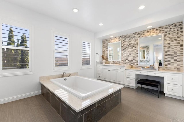 bathroom featuring recessed lighting, a bath, plenty of natural light, and vanity