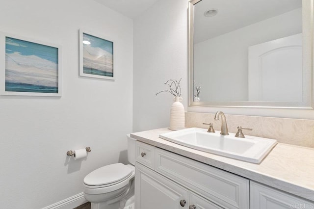 bathroom with baseboards, vanity, and toilet