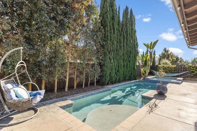view of swimming pool with a fenced backyard, a pool with connected hot tub, and a patio
