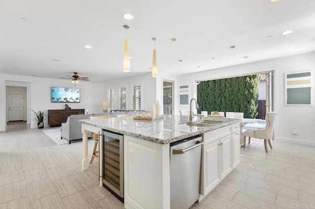 kitchen with a sink, plenty of natural light, open floor plan, beverage cooler, and a center island with sink