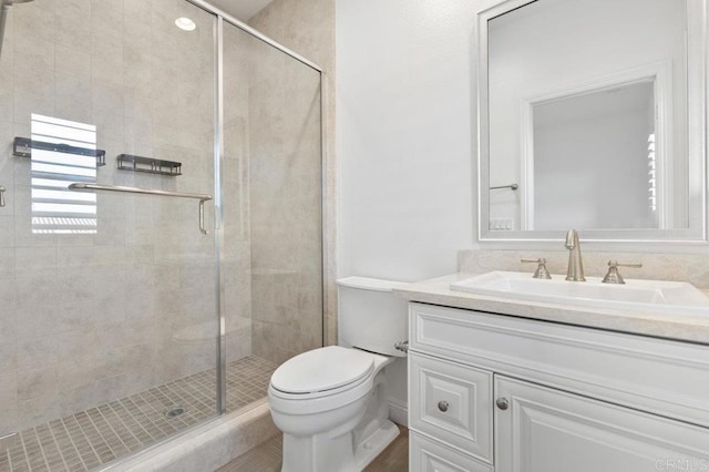 full bathroom featuring a shower stall, toilet, and vanity