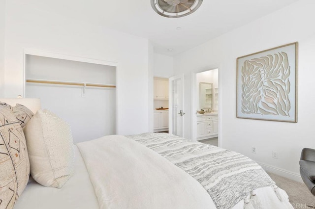 carpeted bedroom with ensuite bathroom, baseboards, a sink, and a closet