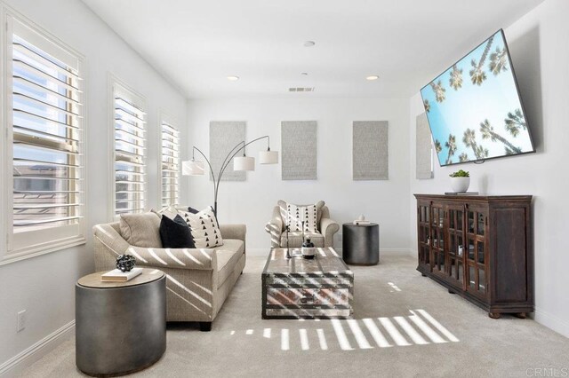 carpeted living area with plenty of natural light, visible vents, and baseboards