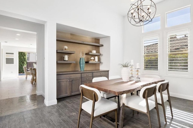 dining space with a chandelier, dark wood finished floors, and baseboards