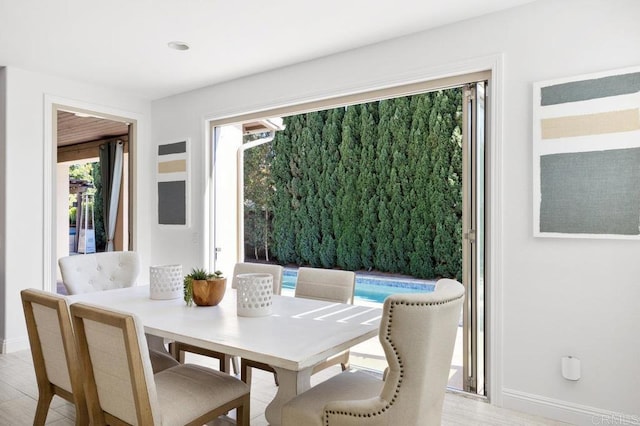 dining room featuring baseboards, light wood-style floors, and a healthy amount of sunlight