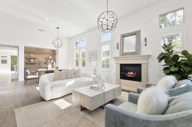 living area with recessed lighting, wood finished floors, visible vents, a chandelier, and a glass covered fireplace