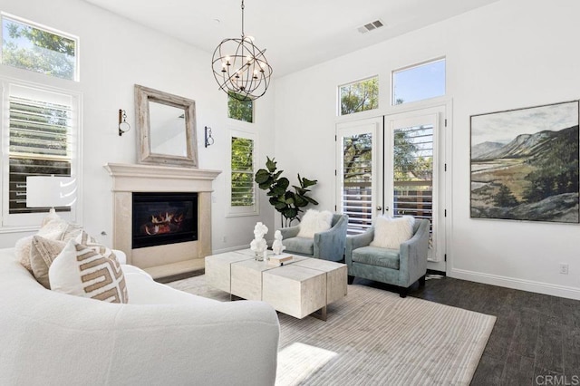 living room with wood finished floors, visible vents, baseboards, a glass covered fireplace, and a notable chandelier