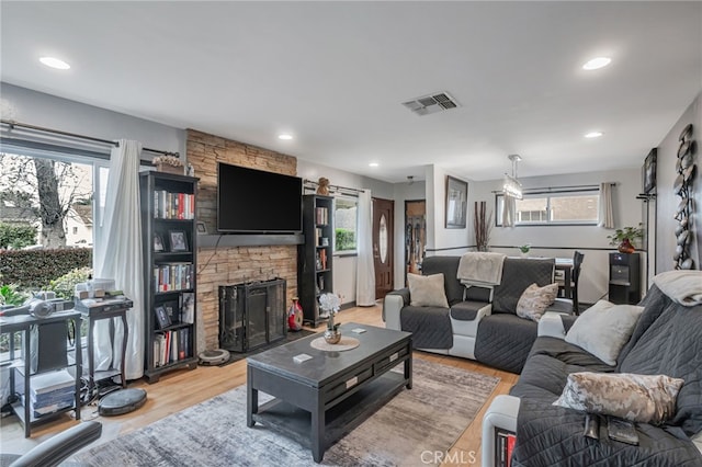 living room featuring recessed lighting, a fireplace, visible vents, and light wood-type flooring