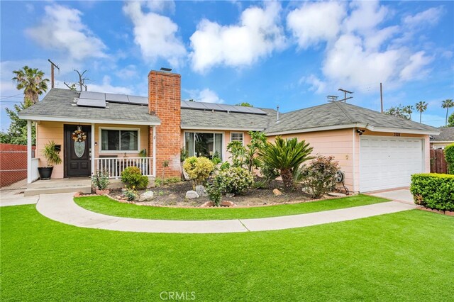 ranch-style home featuring roof mounted solar panels, covered porch, a front yard, fence, and an attached garage