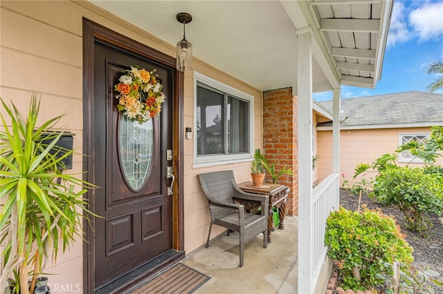 entrance to property with a porch and brick siding