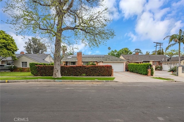 ranch-style home with a residential view, driveway, an attached garage, and solar panels