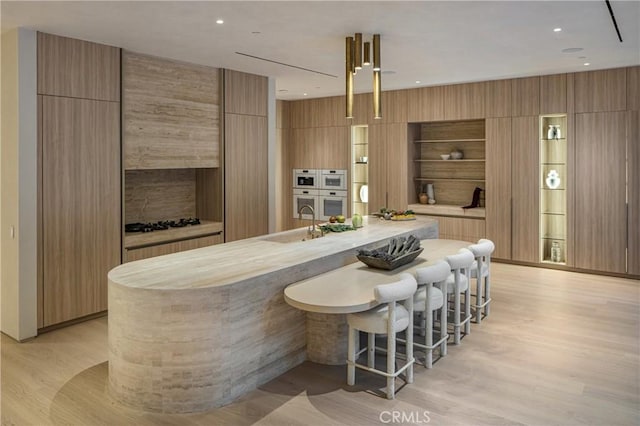 17177 Adlon Rd, Encino, CA 91436 - kitchen featuring light countertops, a kitchen breakfast bar, a large island with sink, light wood-type flooring, and modern cabinets