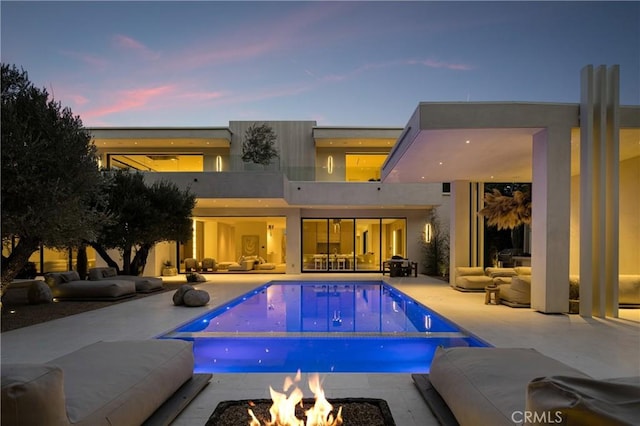 17177 Adlon Rd, Encino, CA 91436 - rear view of property featuring stucco siding, a patio, an outdoor pool, and an outdoor living space with a fire pit