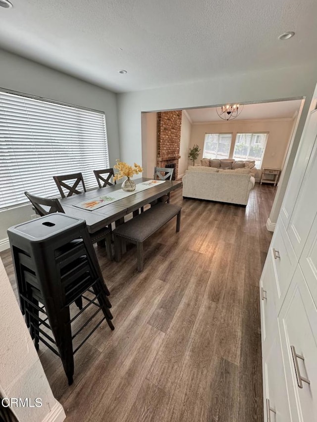 571 Citation Way, Newbury Park, CA 91320 - dining area with a brick fireplace, wood finished floors, baseboards, a textured ceiling, and a notable chandelier