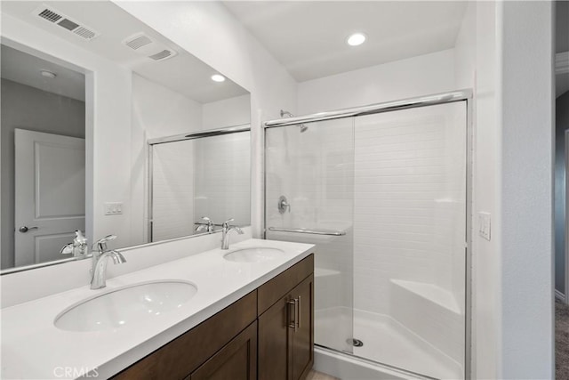 full bathroom featuring visible vents, a sink, a shower stall, and double vanity