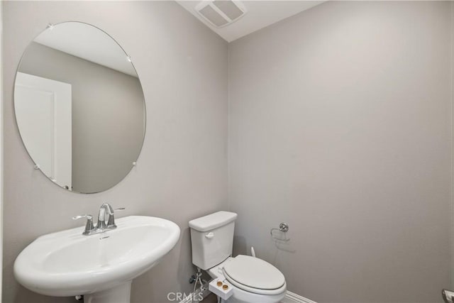 bathroom with toilet, a sink, visible vents, and baseboards