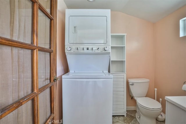 bathroom featuring toilet, tile patterned flooring, stacked washer and clothes dryer, and vaulted ceiling
