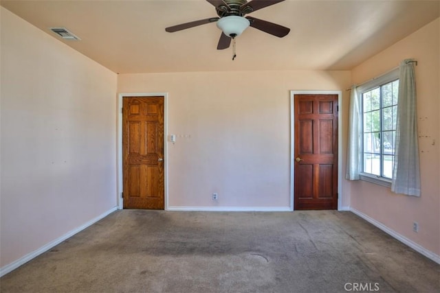 empty room with baseboards, visible vents, ceiling fan, and carpet floors