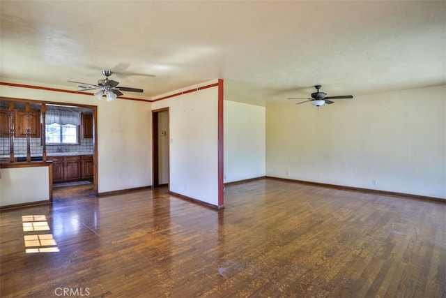 unfurnished living room featuring ceiling fan, baseboards, and dark wood-type flooring