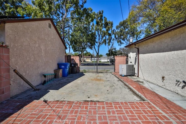 exterior space featuring stucco siding, fence, a gate, and central AC unit