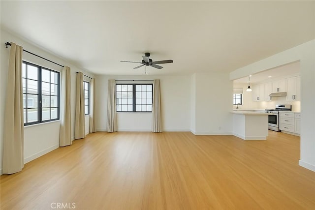 unfurnished living room with baseboards, light wood-type flooring, and a ceiling fan