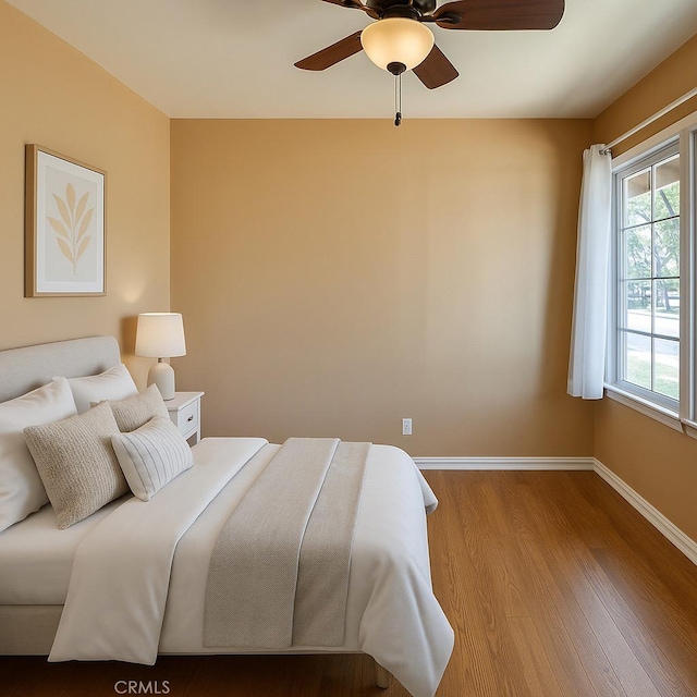 bedroom with wood finished floors, ceiling fan, and baseboards