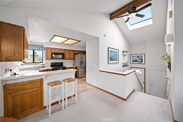 2344 Snowberry Ct, Avila Beach, CA 93424 - kitchen with a sink, a peninsula, brown cabinetry, black appliances, and lofted ceiling with skylight