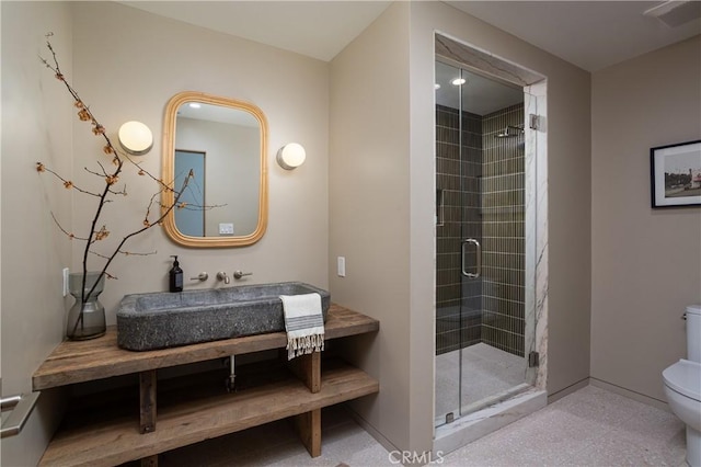 bathroom with visible vents, toilet, a sink, baseboards, and a stall shower