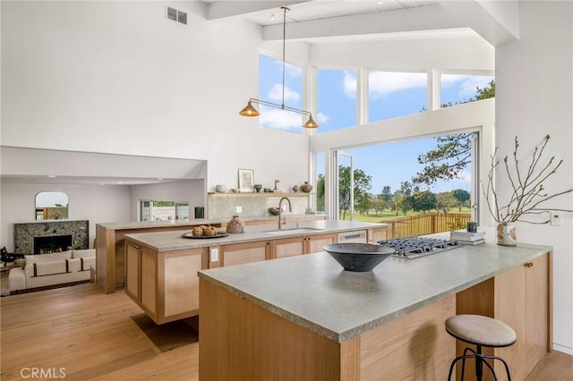 kitchen with stainless steel gas stovetop, visible vents, light brown cabinets, a sink, and a kitchen bar