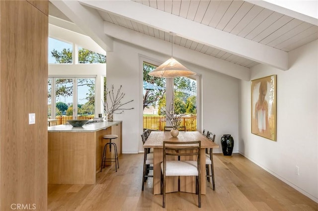 dining area with light wood finished floors, baseboards, vaulted ceiling with beams, and wooden ceiling