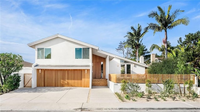view of front facade featuring concrete driveway, fence, stucco siding, and a garage