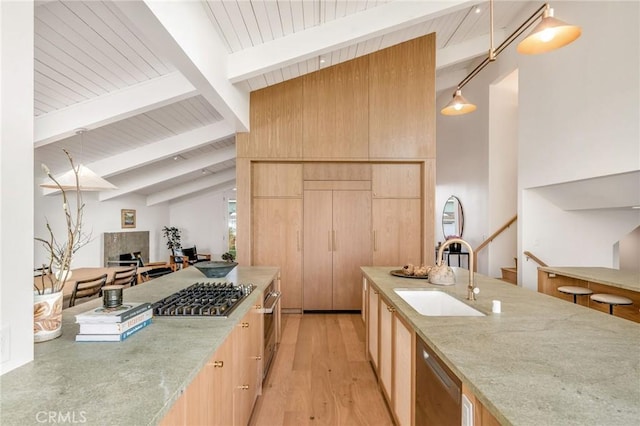 kitchen featuring light brown cabinets, a sink, vaulted ceiling with beams, wooden ceiling, and light stone countertops
