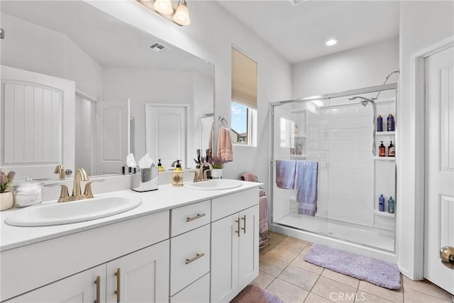 full bath with double vanity, a sink, a stall shower, and tile patterned flooring