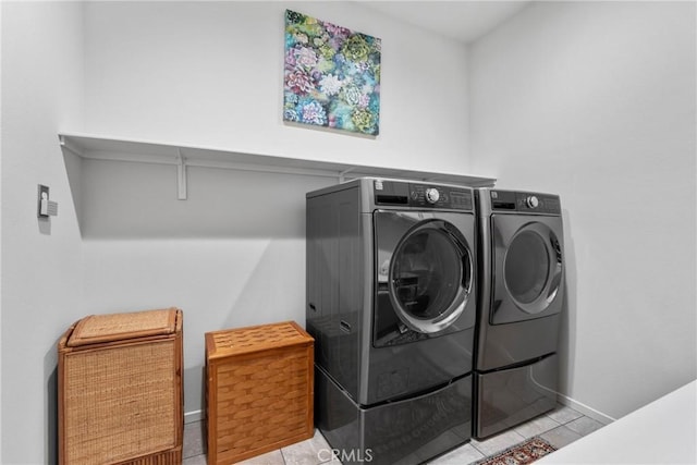 laundry room with washing machine and clothes dryer, baseboards, laundry area, and tile patterned floors