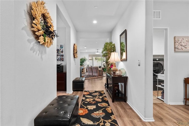 corridor featuring baseboards, washer / clothes dryer, visible vents, and wood finished floors