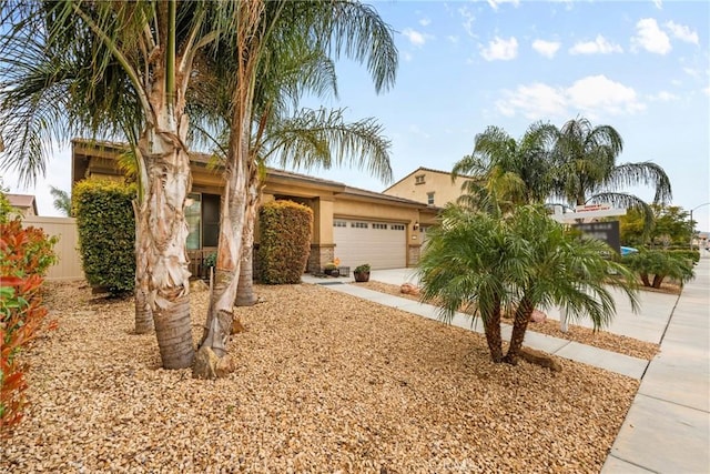 view of front of home featuring stucco siding, a garage, concrete driveway, and fence