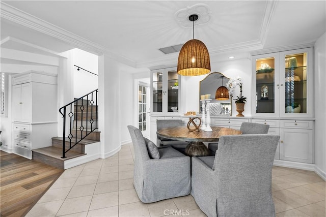 dining area featuring baseboards, ornamental molding, light tile patterned floors, and stairway