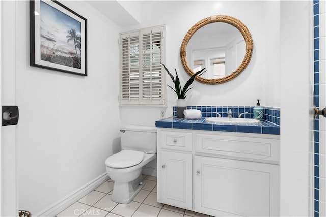 bathroom featuring vanity, baseboards, tile patterned floors, and toilet