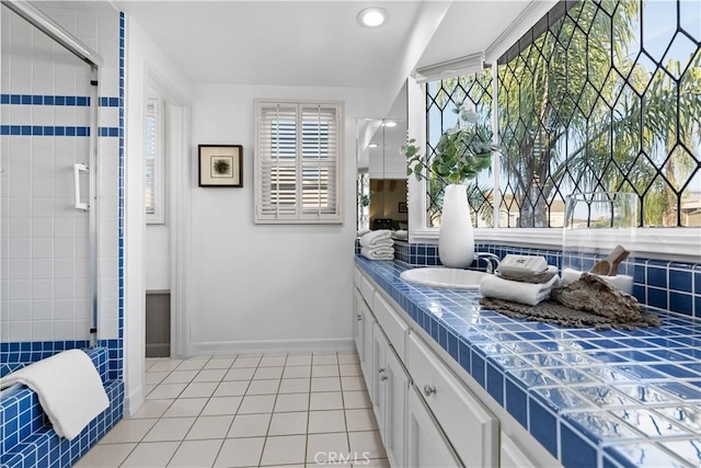 bathroom with tile patterned flooring, a tile shower, vanity, baseboards, and recessed lighting