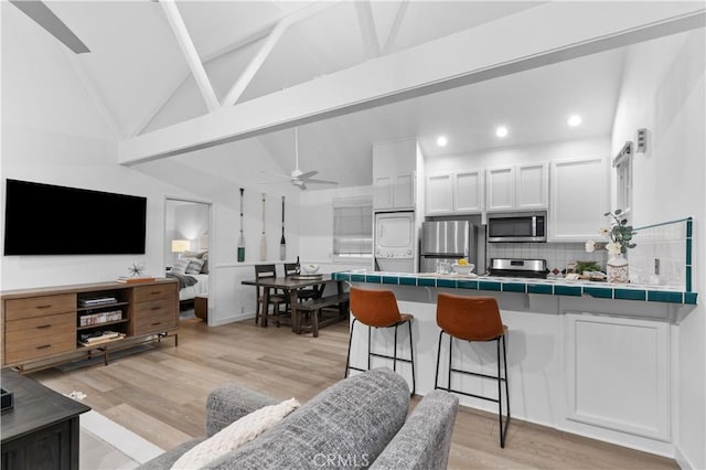 living area featuring a ceiling fan, recessed lighting, vaulted ceiling with beams, and light wood-type flooring