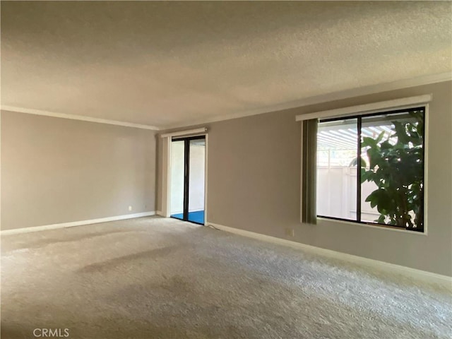 carpeted spare room featuring baseboards, a textured ceiling, and crown molding