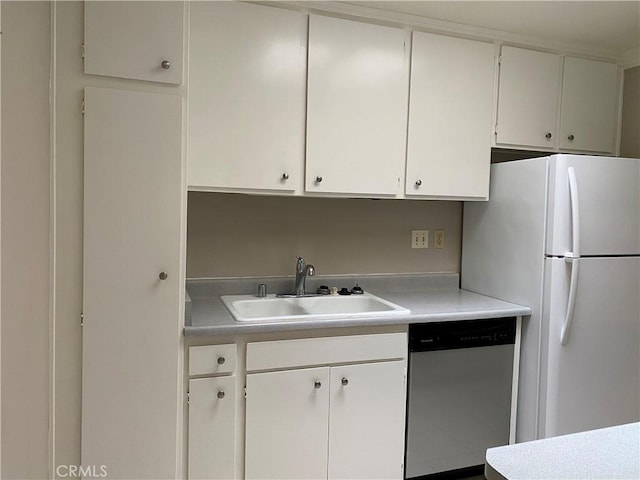 kitchen featuring white cabinetry, light countertops, stainless steel dishwasher, a sink, and freestanding refrigerator