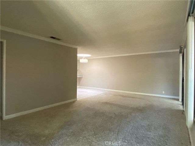carpeted spare room with baseboards, ornamental molding, and visible vents