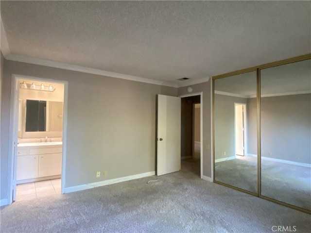 unfurnished bedroom with a textured ceiling, a sink, crown molding, and light carpet